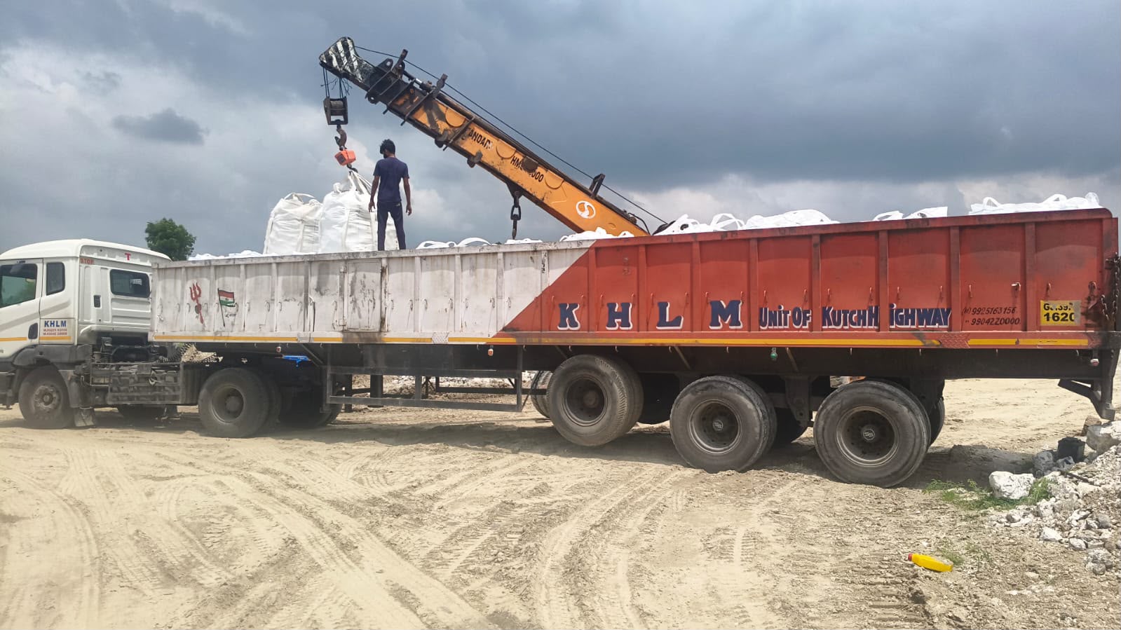 Jumbo bags of mineral material being loaded onto a truck by crane